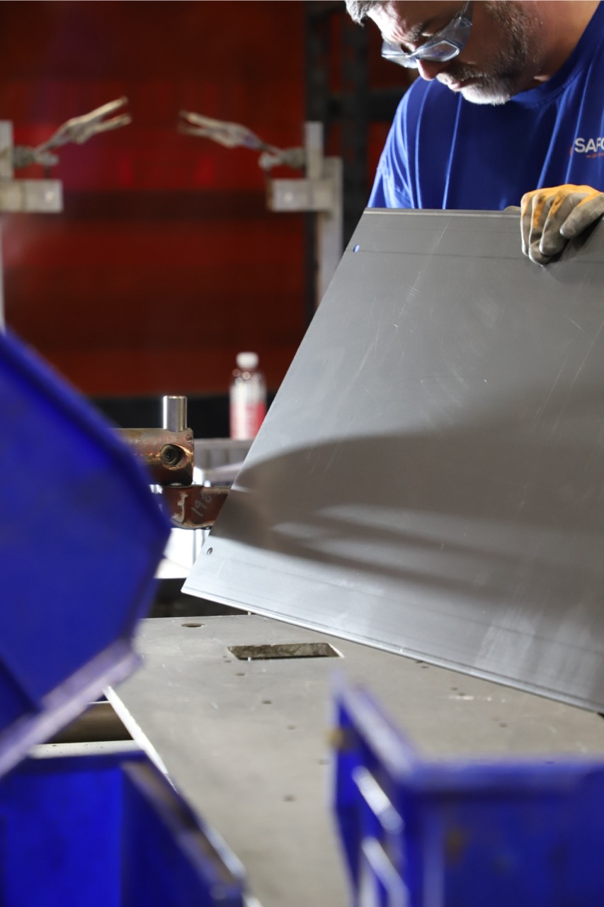 Engineer in safety glasses assembling a mechanical prototype at a workstation